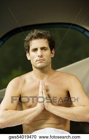 Stock Image - Portrait of a mid adult man sitting in a prayer position. Fotosearch