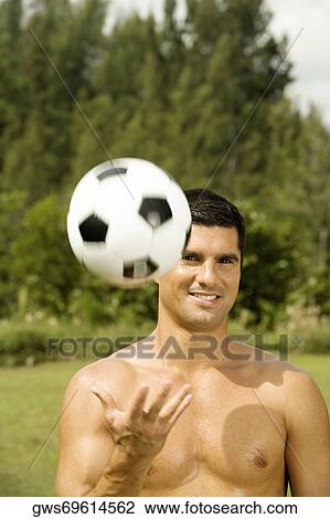 Stock Image - Portrait of a mid adult man tossing a soccer ball. Fotosearch