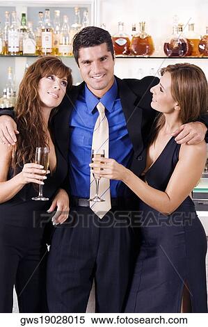 Stock Photography - Portrait of a mid adult man with his arms over two young women. Fotosearch