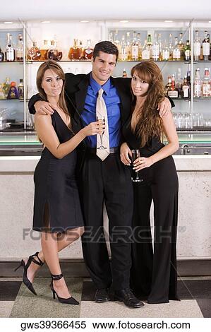 Portrait of a mid adult man with his arms over two young women View Large Photo Image Stock Photography - Portrait of a mid adult man with his arms over two young women. Fotosearch