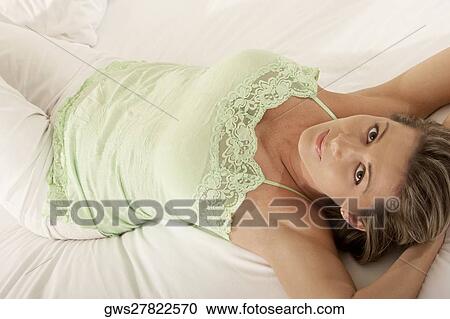 Portrait of a mid adult woman lying on the bed View Large Photo Image Stock Image - Portrait of a mid adult woman lying on the bed. Fotosearch