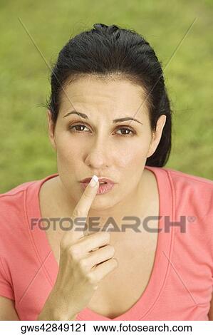 Portrait of a mid adult woman with her finger on her lips View Large Photo Image Stock Image - Portrait of a mid adult woman with her finger on her lips. Fotosearch