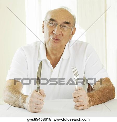Stock Photo - Portrait of a senior man holding a fork with a table knife. Fotosearch