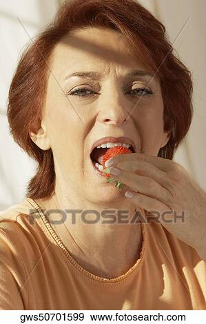 Portrait of a senior woman eating a strawberry View Large Photo Image Stock Photo - Portrait of a senior woman eating a strawberry. Fotosearch