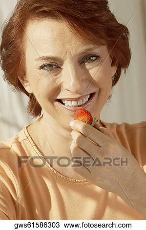 Portrait of a senior woman holding a strawberry View Large Photo Image Stock Image - Portrait of a senior woman holding a strawberry. Fotosearch
