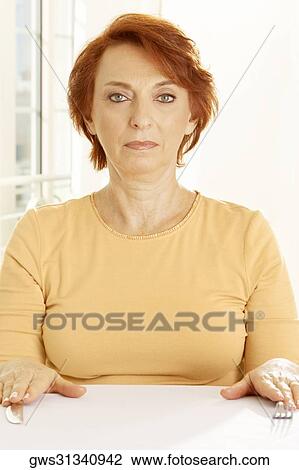 Stock Image - Portrait of a senior woman seated at the table. Fotosearch