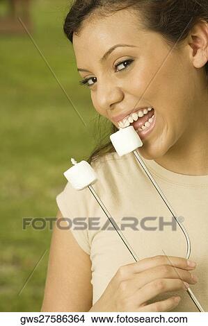 Portrait of a teenage girl eating marshmallows on a skewer View Large Photo Image Picture - Portrait of a teenage girl eating marshmallows on a skewer. Fotosearch