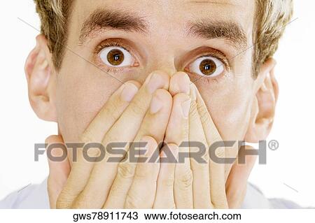Stock Image - Portrait of a young man covering his mouth with his hands. Fotosearch