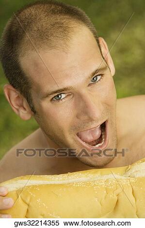 Portrait of a young man eating a loaf of baked bread View Large Photo Image Stock Photography - Portrait of a young man eating a loaf of baked bread. Fotosearch