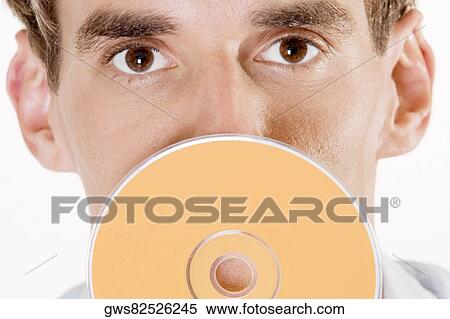 Portrait of a young man holding a CD in front of his mouth View Large Photo Image Stock Photography - Portrait of a young man holding a CD in front of his mouth. Fotosearch