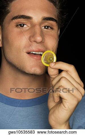 Stock Image - Portrait of a young man holding a condom. Fotosearch