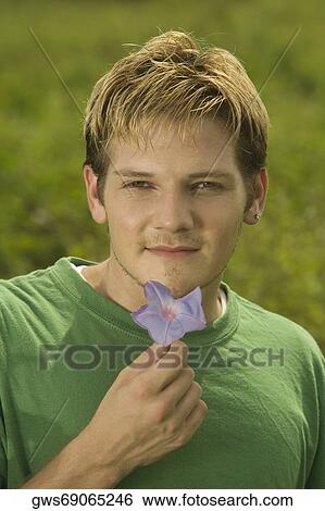 Portrait of a young man holding a flower View Large Photo Image Stock Photograph - Portrait of a young man holding a flower. Fotosearch