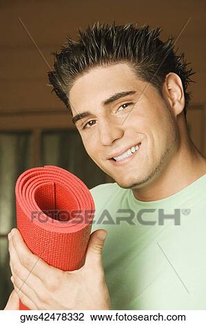 Portrait of a young man holding a rolled up exercise mat View Large Photo Image Stock Image - Portrait of a young man holding a rolled up exercise mat. Fotosearch
