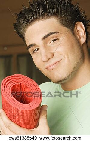 Portrait of a young man holding a rolled up exercise mat View Large Photo Image Stock Photo - Portrait of a young man holding a rolled up exercise mat. Fotosearch
