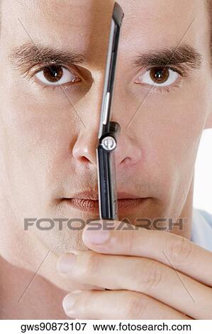 Portrait of a young man holding a mobile phone against his face View Large Photo Image Stock Photo - Portrait of a young man holding a mobile phone against his face. Fotosearch