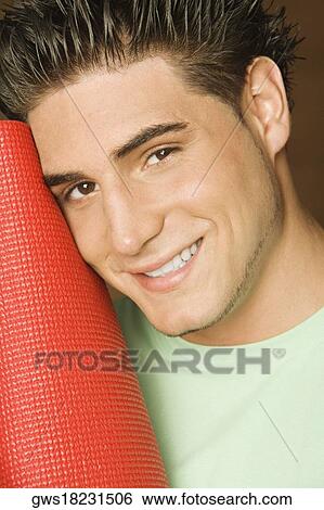 Portrait of a young man holding a rolled up exercise mat View Large Photo Image Stock Photograph - Portrait of a young man holding a rolled up exercise mat. Fotosearch