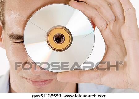 Portrait of a young man looking through the hole of a CD View Large Photo Image Stock Photo - Portrait of a young man looking through the hole of a CD. Fotosearch
