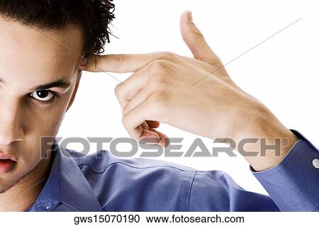 Portrait of a young man pointing to the side of his head View Large Photo Image Stock Image - Portrait of a young man pointing to the side of his head. Fotosearch