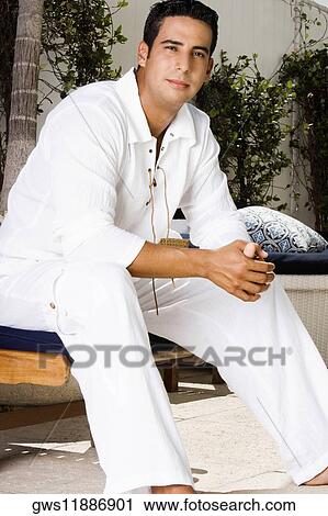 Portrait of a young man sitting on a Chaise Longue with his hands clasped View Large Photo Image Stock Image - Portrait of a young man sitting on a Chaise Longue with his hands clasped. Fotosearch