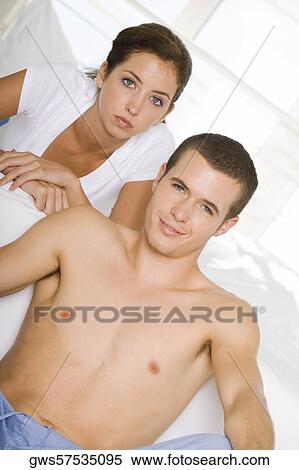Portrait of a young man sitting on the floor with a young woman lying on the bed View Large Photo Image Stock Photography - Portrait of a young man sitting on the floor with a young woman lying on the bed. Fotosearch
