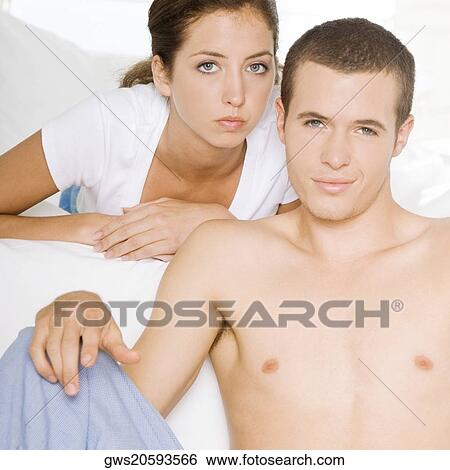 Portrait of a young man sitting with a young woman lying on the bed View Large Photo Image Stock Photograph - Portrait of a young man sitting with a young woman lying on the bed. Fotosearch