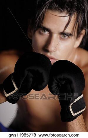 Stock Photo - Portrait of a young man wearing boxing gloves. Fotosearch