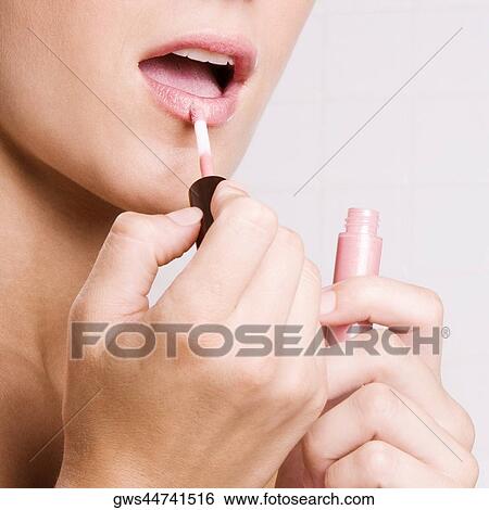 Stock Photograph - Portrait of a young woman applying lipstick. Fotosearch