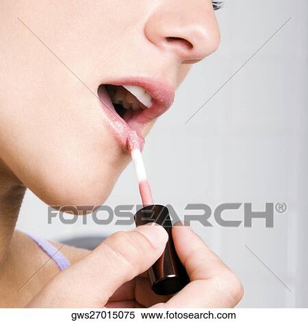 Portrait of a young woman applying lipstick View Large Photo Image Stock Photography - Portrait of a young woman applying lipstick. Fotosearch