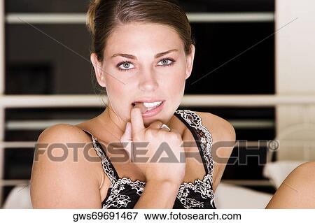 Stock Photo - Portrait of a young woman biting her finger nails. Fotosearch