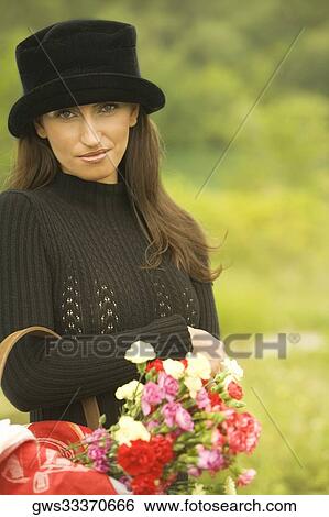 Stock Photograph - Portrait of a young woman carrying a bouquet of flowers. Fotosearch
