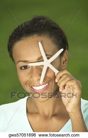 Portrait of a young woman covering her eye with a starfish View Large Photo Image Stock Photograph - Portrait of a young woman covering her eye with a starfish. Fotosearch