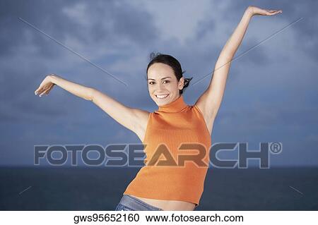 Portrait of a young woman dancing with her arms raised View Large Photo Image Stock Image - Portrait of a young woman dancing with her arms raised. Fotosearch