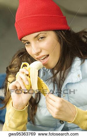 Portrait of a young woman eating a banana View Large Photo Image Stock Photo - Portrait of a young woman eating a banana. Fotosearch