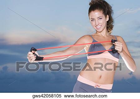 Portrait of a young woman exercising with a resistance band View Large Photo Image Stock Photography - Portrait of a young woman exercising with a resistance band. Fotosearch