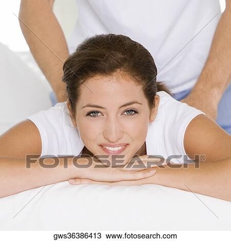 Stock Image - Portrait of a young woman getting a back massage from a young man. Fotosearch