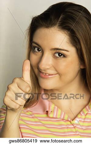 Portrait of a young woman giving a thumbs up gesture View Large Photo Image Stock Photo - Portrait of a young woman giving a thumbs up gesture. Fotosearch