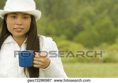 Portrait of a young woman holding a cup of coffee View Large Photo Image Stock Photo - Portrait of a young woman holding a cup of coffee. Fotosearch