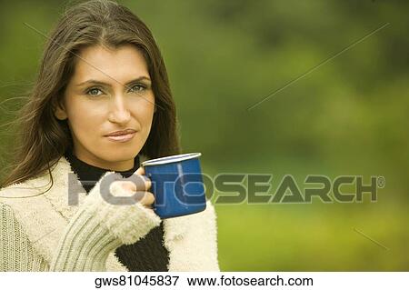 Portrait of a young woman holding a mug View Large Photo Image Stock Photo - Portrait of a young woman holding a mug. Fotosearch