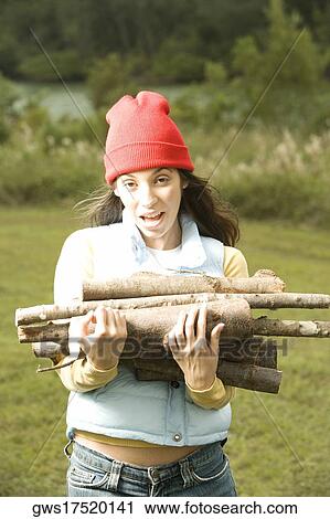 Portrait of a young woman holding a heap of firewood View Large Photo Image Stock Image - Portrait of a young woman holding a heap of firewood. Fotosearch
