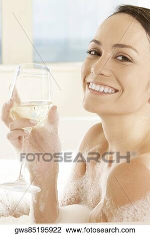 Portrait of a young woman holding a glass of white wine in the bathtub View Large Photo Image Stock Image - Portrait of a young woman holding a glass of white wine in the bathtub. Fotosearch