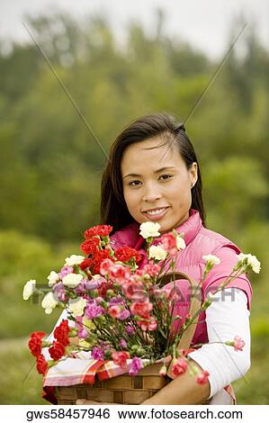 Stock Photograph - Portrait of a young woman holding a basket of flowers. Fotosearch