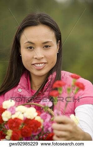 Stock Photo - Portrait of a young woman holding flowers. Fotosearch