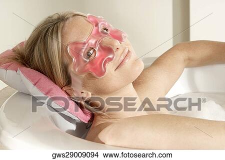 Portrait of a young woman in a bathtub wearing an eye mask View Large Photo Image Picture - Portrait of a young woman in a bathtub wearing an eye mask. Fotosearch