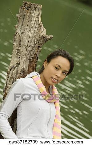 Portrait of a young woman leaning against a tree stump View Large Photo Image Stock Photo - Portrait of a young woman leaning against a tree stump. Fotosearch