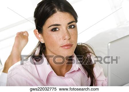 Stock Photography - Portrait of a young woman lying in front of a laptop. Fotosearch