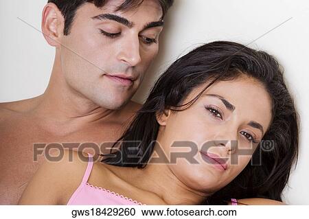 Stock Image - Portrait of a young woman lying with a young man on the bed. Fotosearch