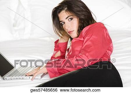 Portrait of a young woman lying with a laptop on the bed View Large Photo Image Stock Photograph - Portrait of a young woman lying with a laptop on the bed. Fotosearch