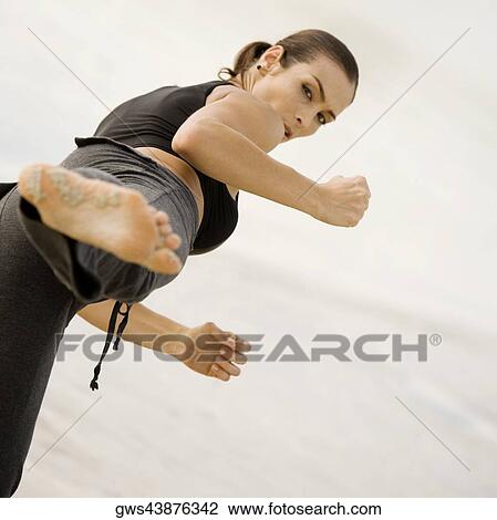 Stock Image - Portrait of a young woman practicing martial arts on the beach. Fotosearch