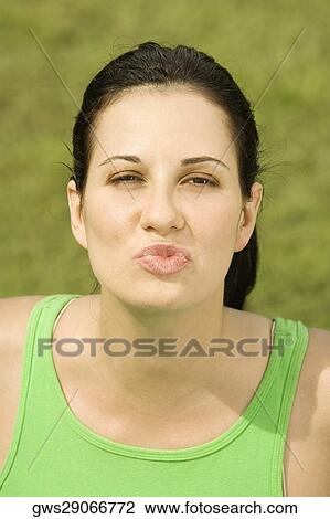 Stock Image - Portrait of a young woman puckering her lips. Fotosearch