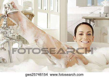 Picture - Portrait of a young woman reclining in a bubble bath. Fotosearch